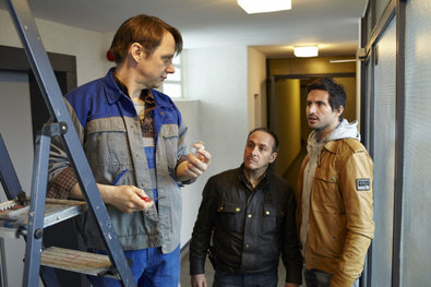 Die Suche nach dem Eigentümer des Entführer-Vans führt Semir (Erdogan Atalay, M.) und Ben (Tom Beck, r.) in einen großen Wohnblock, wo sie den Hausmeister Sven Wegener (Arndt Schwering-Sohnrey) befragen.